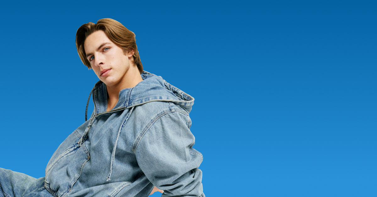 Person wearing a denim outfit against a clear blue sky