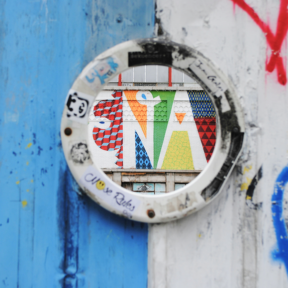 Circular artwork with geometric patterns on a textured wall with graffiti.