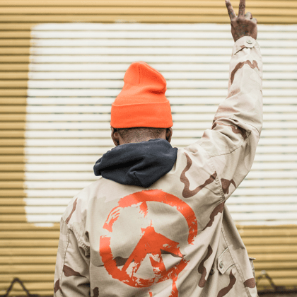 Person wearing a camouflage jacket with a peace symbol.